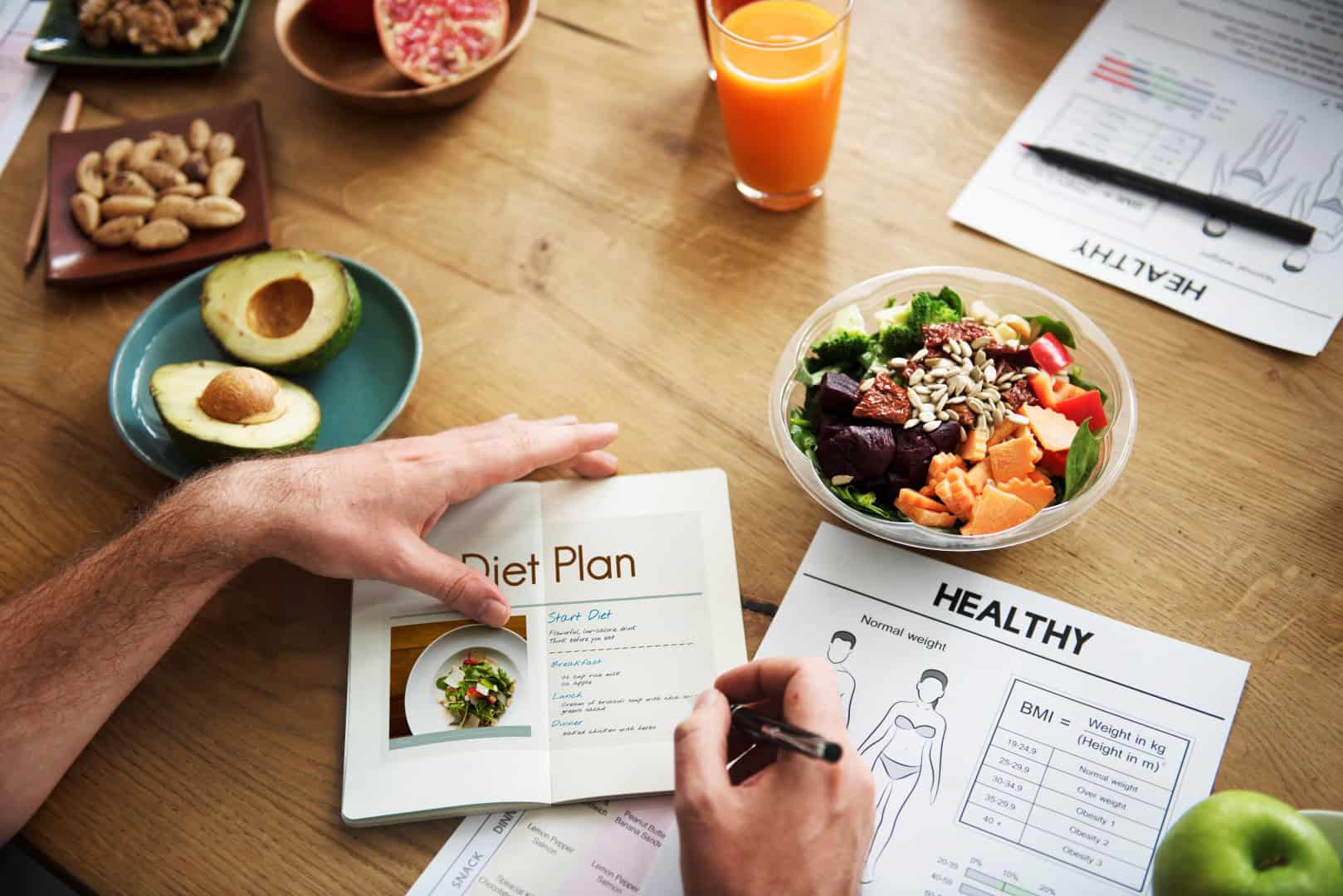 Dietitian writing a diet plan on a table filled with healthy food